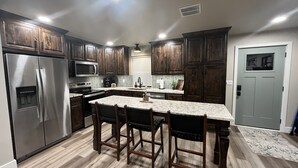A modern kitchen with dark wooden cabinets, stainless steel appliances, and a marble countertop.