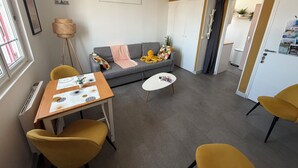 A modern living room with a sofa, a coffee table, and two yellow chairs. There is a small table with a decorative item and a lamp.