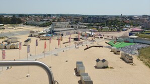 A beach area with tents, flags, and a building in the background.