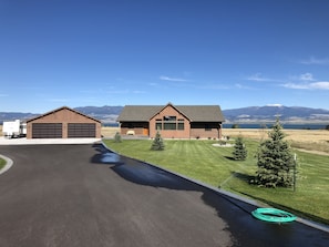 A modern two-story house with a garage, a well-maintained lawn, and a view of mountains in the background.