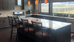Una cocina moderna con una isla grande, armarios de madera oscura e iluminación colgante.