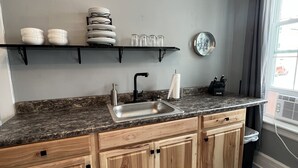 Eine moderne Küche mit Holzschränken, einer Granit-Arbeitsplatte, einer Edelstahl-Spüle und einem Teppich mit Sonnenblumenmuster.