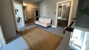 Ein modernes Wohnzimmer mit großem Teppich, einem weißen Sofa und einem Spiegel, der den Raum wiederspiegelt.