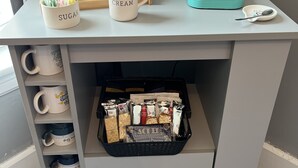 Eine Kaffeestation mit einer Keurig-Maschine, beschrifteten Tassen und einem Kaffeeschild.