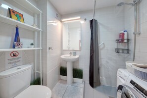 Un bagno moderno con WC, lavandino, doccia e lavatrice.