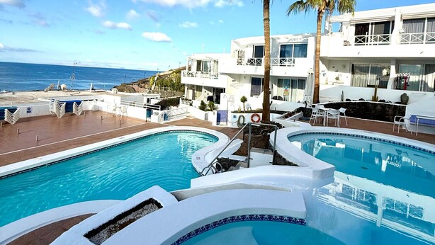 Ett semesterparadis med flera pooler, palmer och utsikt över havet.