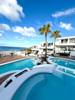 A resort with multiple swimming pools, palm trees, and a view of the ocean. - Suite Infinity Ocean - Pool and Sea view By LVH (Puerto del Carmen)