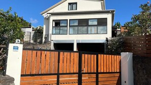 Een twee verdiepingen tellend huis met een garage, een houten poort en een helderblauwe lucht.