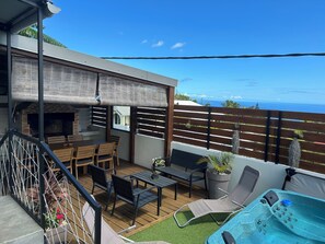Un patio exterior cubierto con una parrilla, zona de estar y un jacuzzi.