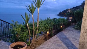 A stone pathway leading to a balcony overlooking a coastal area with vegetation and a view of the sea. - 100m de la Plage,maison Face à la Mer! Idéale Pour de Belles Vacances en Famille (Brando)