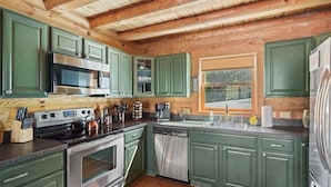 A kitchen with green cabinets, stainless steel appliances, and wooden ceiling beams. - 5BR MOUNTAIN LODGE: 2MIN TO SLOPES, ARCADES FOOSBALL, GOLF WATERPARK, SLEEPS S14 (McGaheysville)