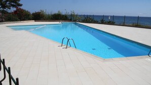 Une piscine rectangulaire à l’eau d’un bleu limpide, entourée d’une terrasse carrelée.
