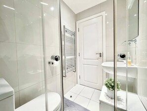 A modern bathroom with a glass shower enclosure, a white toilet, a glass door, and a white sink with a mirror. - 3-bed Pimlico Flat, Garden | victoria tate britain (Greater London)