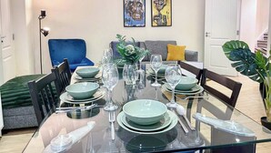 Een eethoek met een glazen tafel, gedekt voor zes personen, omringd door stoelen.