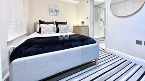 Een moderne slaapkamer met een bed, nachtkastjes, een spiegel en een inloopkast.
