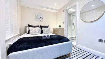 A modern bedroom with a bed, bedside tables, a mirror, and a walk-in closet.