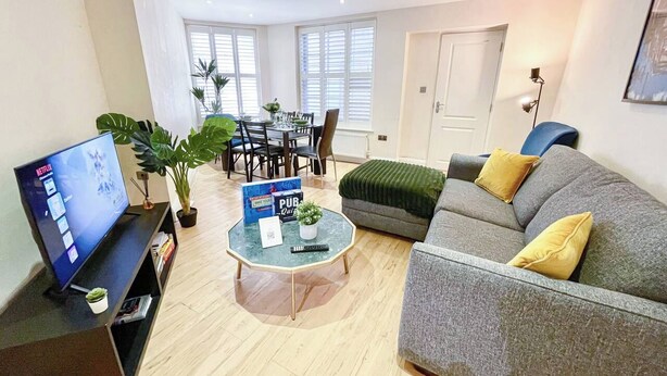 Een woonkamer met een televisie, een salontafel, een bank en een eethoek met stoelen en een tafel.