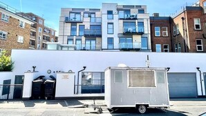 Un edificio de varios pisos con fachada blanca, un pequeño remolque blanco y un letrero que dice 'Pindaria House'.