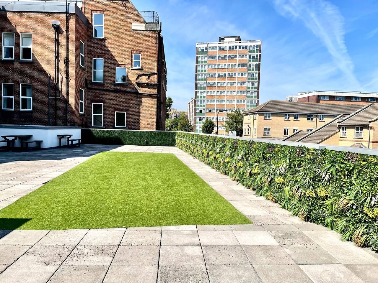 A courtyard with a well-maintained lawn, a hedge, and a paved walkway.