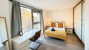 Una habitación de hotel con cama, mesitas de noche, escritorio y ventana.