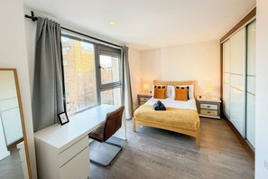 A hotel room with a bed, bedside tables, a desk, and a window. - 3bdr Hoxton Flat Near Old st, shoreditch + balcony (London)