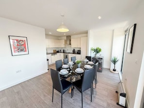 A modern kitchen with white cabinets, a dining table set for six, and a pendant light above. - 3bdr Hoxton Flat Near Old st, shoreditch + balcony (London)