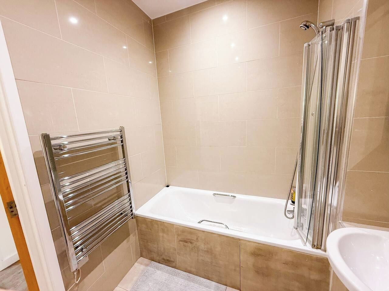 A modern bathroom with a bathtub, a glass shower enclosure, and a towel rack.