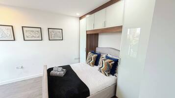 A modern bedroom with a bed, headboard, wall-mounted cabinets, and framed artwork.