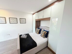 A modern bedroom with a bed, headboard, wall-mounted cabinets, and framed artwork.
