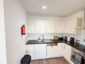 A modern kitchen with white cabinets, a stainless steel sink, and a dishwasher.