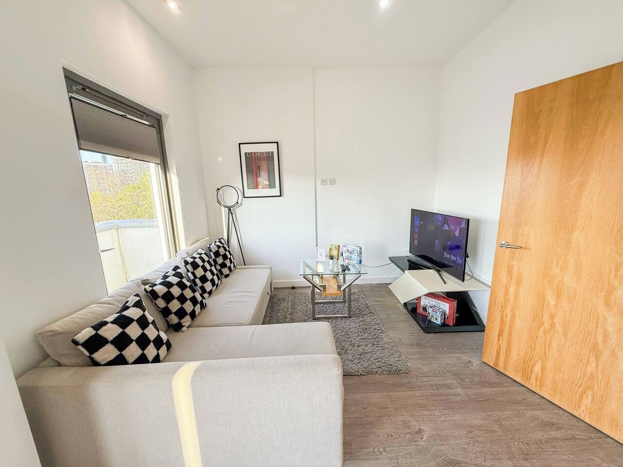 A modern living room with a sofa, a coffee table, a television, and a door.