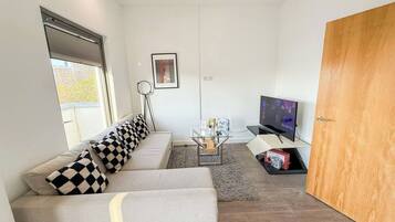 A modern living room with a sofa, a coffee table, a television, and a door.