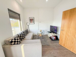 Una sala de estar moderna con un sofá, una mesa de centro, un televisor y una puerta.