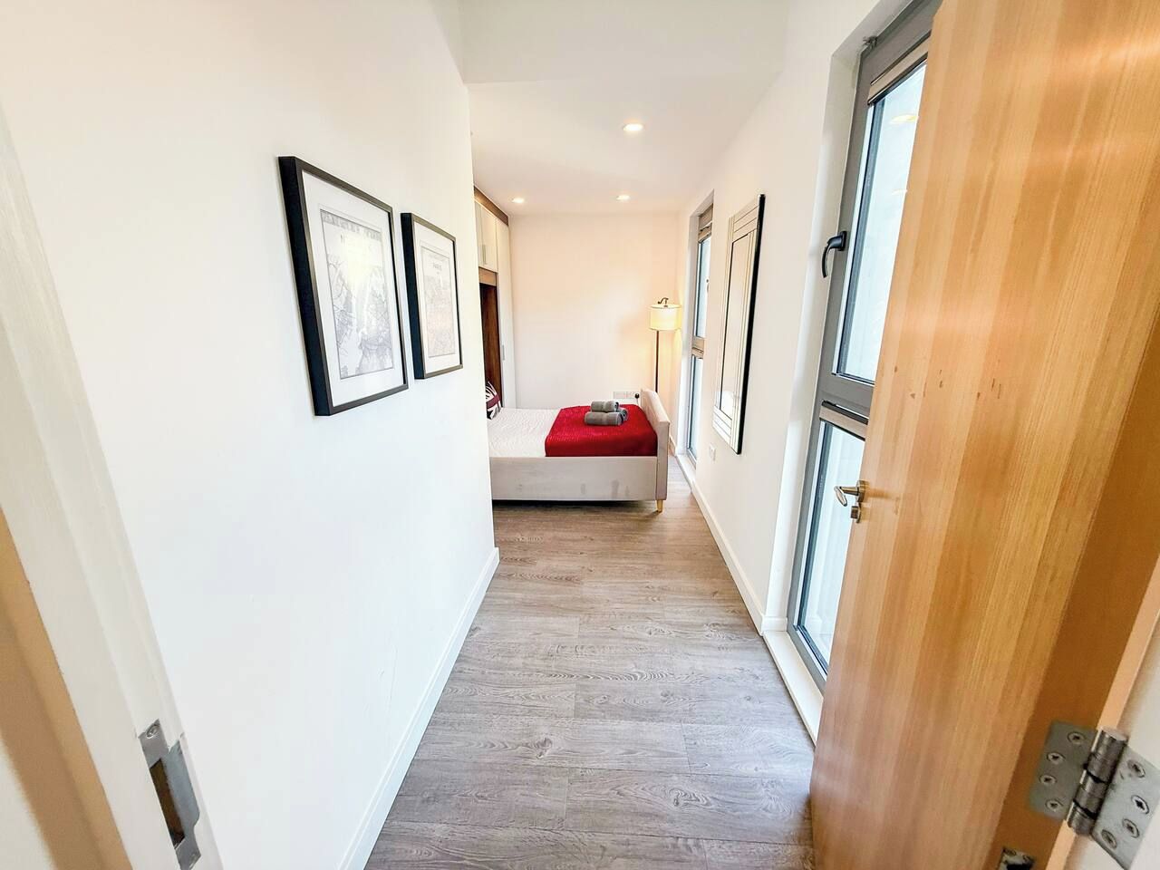 A hallway with a bed, framed pictures on the walls, and a wooden door.