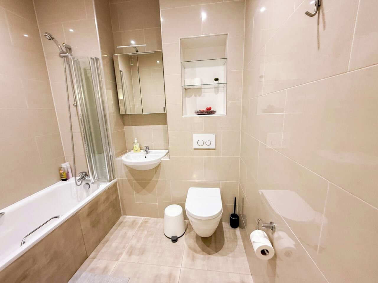 A modern bathroom with a bathtub, sink, toilet, and a glass shower enclosure.