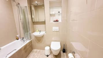 A modern bathroom with a bathtub, sink, toilet, and a glass shower enclosure.