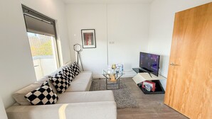 Uma sala de estar moderna com um sofá, uma TV e uma porta de madeira.