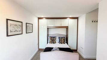 A bedroom with a bed, a bench, and a wardrobe.