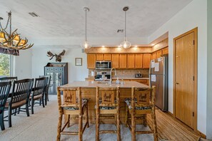 A kitchen with wooden cabinets, a central island, and a dining area with chairs.