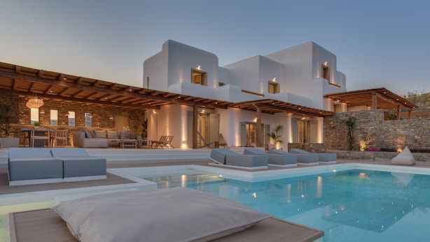 A modern villa with a pool, outdoor seating, and a stone wall. - Villa TROPICAL OASIS, Kalafatis, Mykonos. (Mykonos)