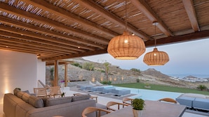 A modern outdoor living area with a pool, seating, and a view of the landscape. - Villa TROPICAL OASIS, Kalafatis, Mykonos. (Mykonos)