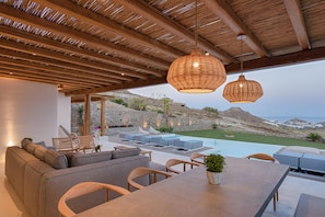 A modern outdoor living area with a pool, seating, and a view of the landscape.