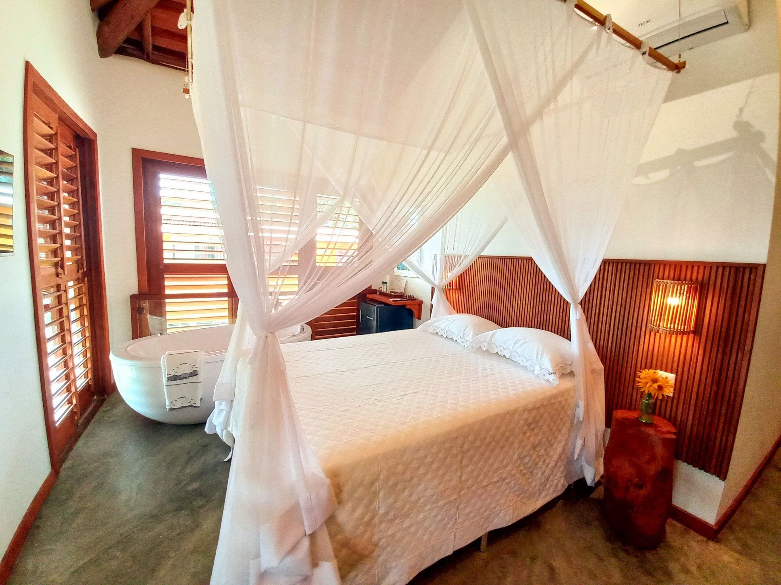 A bedroom with a canopy bed, wooden headboard, bedside tables, and a small red stool.