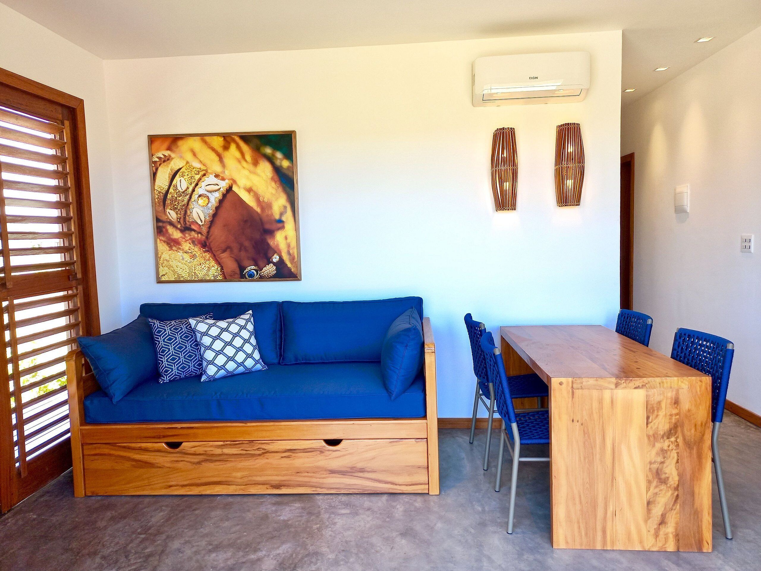 A modern living room with a blue sofa, a wooden dining table, and blue chairs.