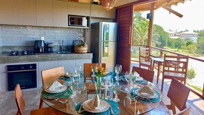 Cocina moderna equipada con microondas, refrigerador y comedor con mesa de vidrio para seis personas.