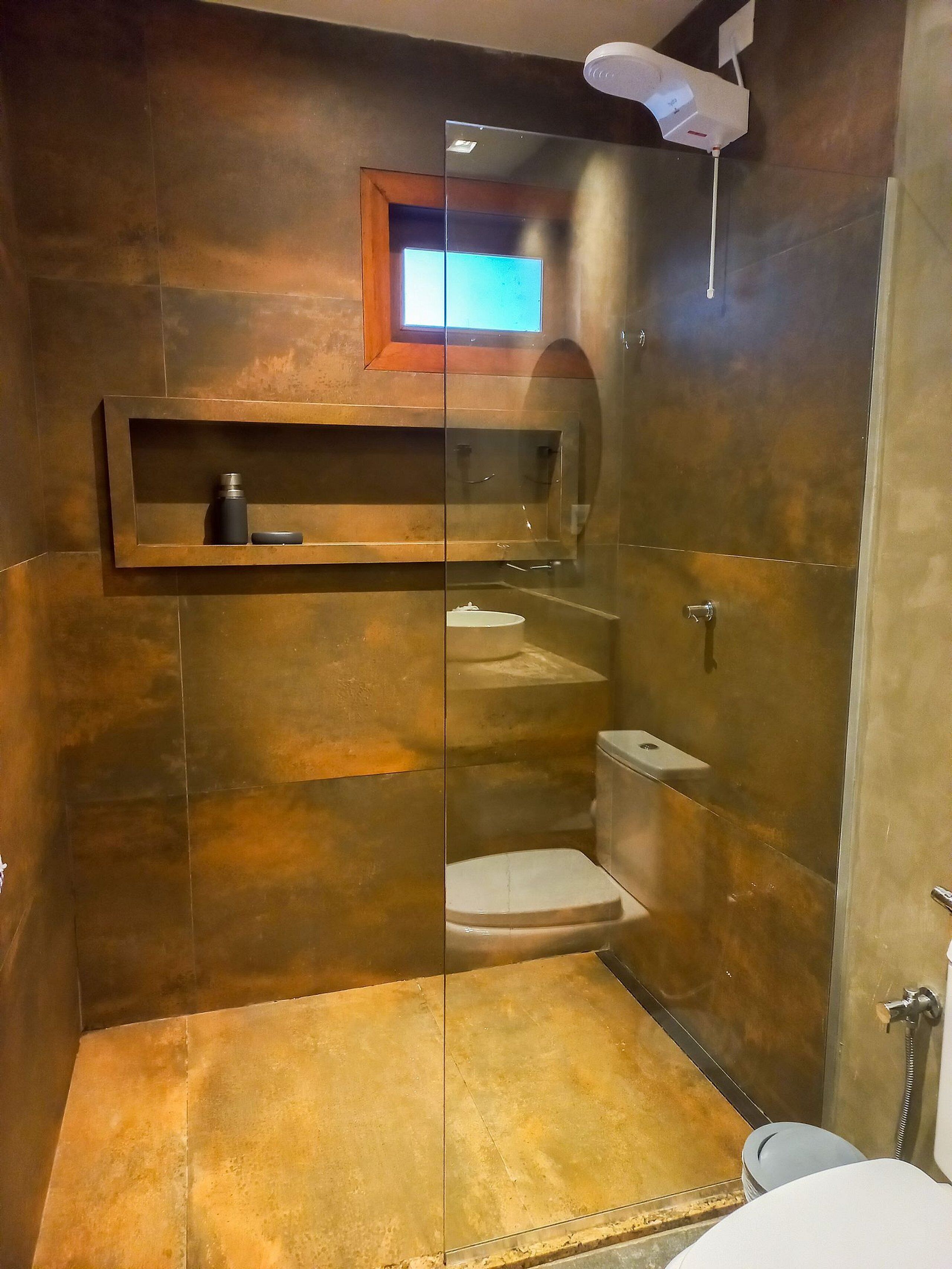 Une salle de bain moderne avec une douche à parois de verre, des toilettes et une étagère contenant des articles de toilette.