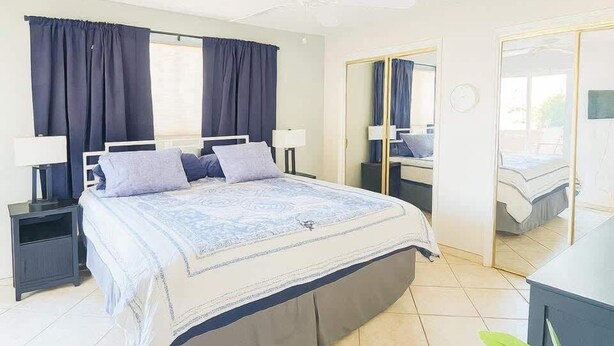 A bedroom with a bed, nightstands, a mirror, and a ceiling fan. - Casa de Conquistadores (Green Valley)