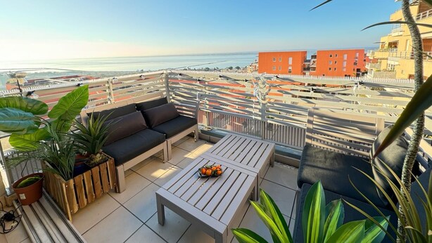 A balcony with a sofa, a table, and potted plants. - Magnifique T3 à 5 min des Plages, Garage Privé et vue Imprenable ! (Sète)
