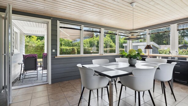 Een moderne keuken met een groot eiland, witte stoelen en uitzicht op groen.