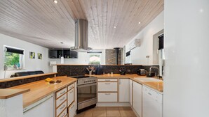 Een moderne keuken met houten aanrecht, een ingebouwde oven en een vaatwasser.